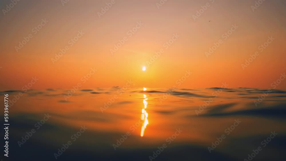 Slow Motion ocean surface from underwater at sunset with rays of light. Crystal clear breaking ocean wave with waving waterline. Sunrise over calm sea. Dawn over horizon, ocean, water - timelapse or