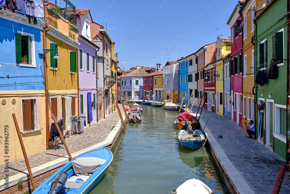 Burano, Venice: Colorful houses of Burano island. Multicolored buildings on fondamenta embankment of narrow water canal with fishing boats and stone bridge, Venice Province, Veneto Region, Italy.
