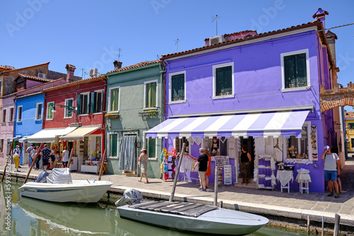 Burano, Venice: Colorful houses of Burano island. Multicolored buildings on fondamenta embankment of narrow water canal with fishing boats and stone bridge, Venice Province, Veneto Region, Italy.