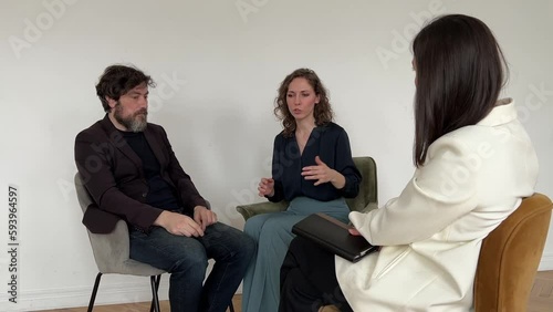 Marital therapy concept. Family couple sitting with back to camera, having appointment with psychologist at office. Psychotherapist helping young family solve their marriage problems