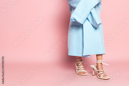 Close-up of a little girl in an oversized adult blue blazer and a heels shoes. isolated on pink background.