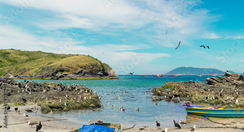 Praia do Forte São Mateus in Cabo Frio, with sea water around it, many fishing boats, beautiful sky with clouds and mountains in the background.