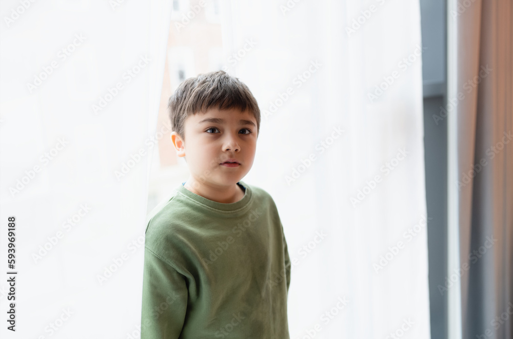 Portrait Kid boy with smiling face looking up standing behind lace curtain with bright light in morning,Positive children concept Portrait Kid boy with smiling face looking up standing behind lace curtain with bright light in morning,Positive children concept