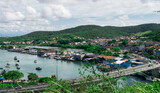 View of the port of Cabo Frio seen from the viewpoint of Nossa Senhora da Guia, with a bridge and many boats sailing through the channel, mountains around and a beautiful blue sky with clouds.