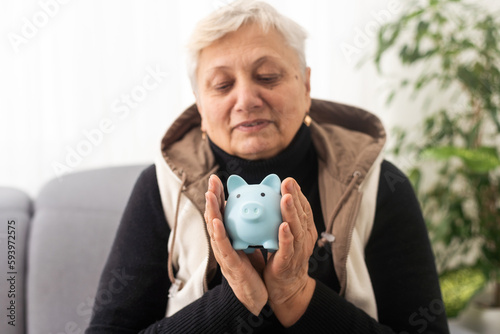 Money management concept. Senior elderly woman is holding a piggy bank