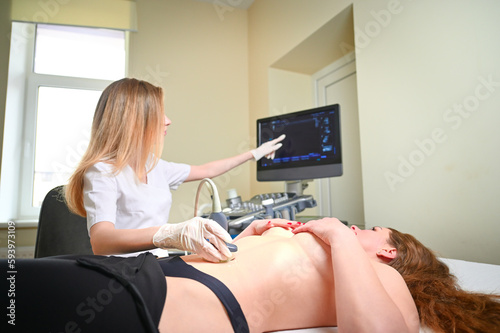 Professional female gynecologist performs an examination of the mammary glands using ultrasound scanner. Breast ultrasound examination. Prevention breast cancer. Screening after plastic surgery. photo