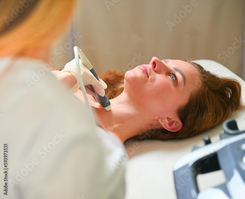 The ultrasound technician do the examination using a transducer. Portrait of a cute girl undergoing a thyroid ultrasound ! TMedical examination and care photo