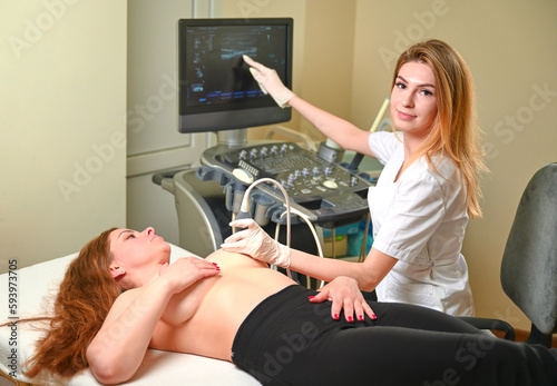 Professional female gynecologist performs an examination of the mammary glands using ultrasound scanner. Breast ultrasound examination. Prevention breast cancer.  Screening after plastic surgery. photo