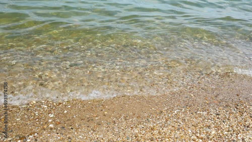 Waves near the shore of a lake, river or sea with clear water. A small pebble beach in sunny weather. Waves near the shore of a lake, river or sea with clear water. A small pebble beach in sunny weather.