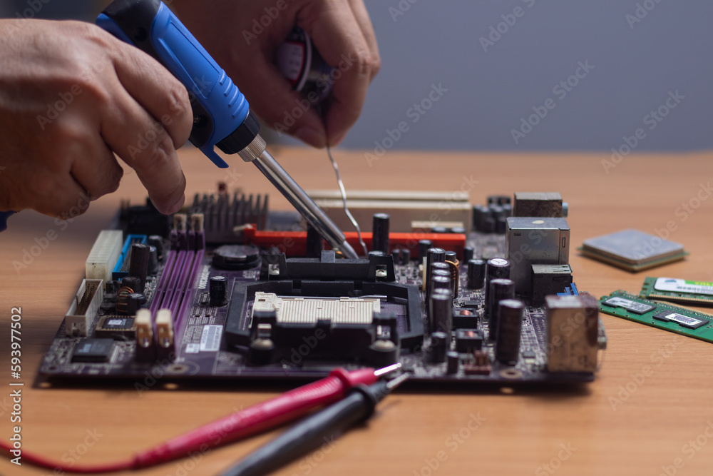 Technician using a soldering iron to repair a circuit board Technician using a soldering iron to repair a circuit board