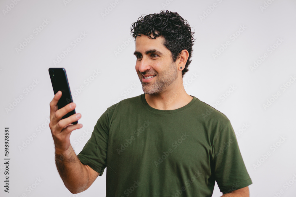 Middle-aged Latin man looking at his cell phone with a smile on a white background. Middle-aged Latin man looking at his cell phone with a smile on a white background.