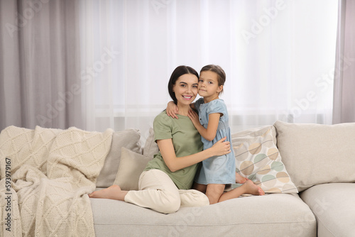 Happy woman and her cute daughter spending time together on sofa at home. Mother's day celebration