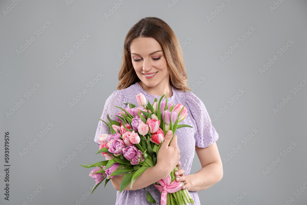 Happy young woman with bouquet of beautiful tulips on grey background Happy young woman with bouquet of beautiful tulips on grey background
