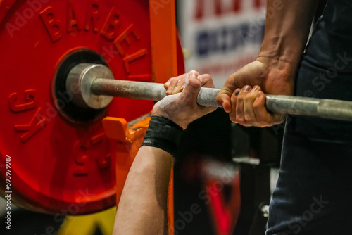 arm powerlifter in wrist wraps to hold heavy barbell before bench press powerlifting competition photo