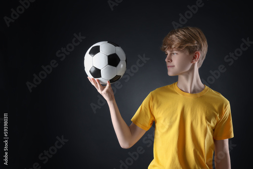 Teenage boy with soccer ball on black background. Space for text