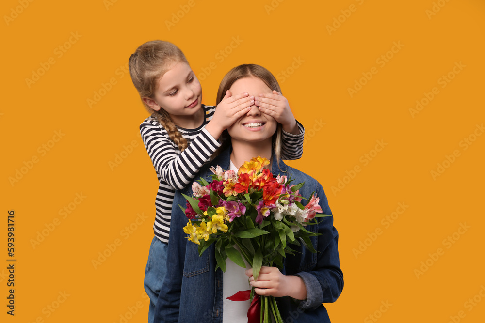 Little daughter congratulating her mom with flowers on orange background. Happy Mother's Day Little daughter congratulating her mom with flowers on orange background. Happy Mother's Day