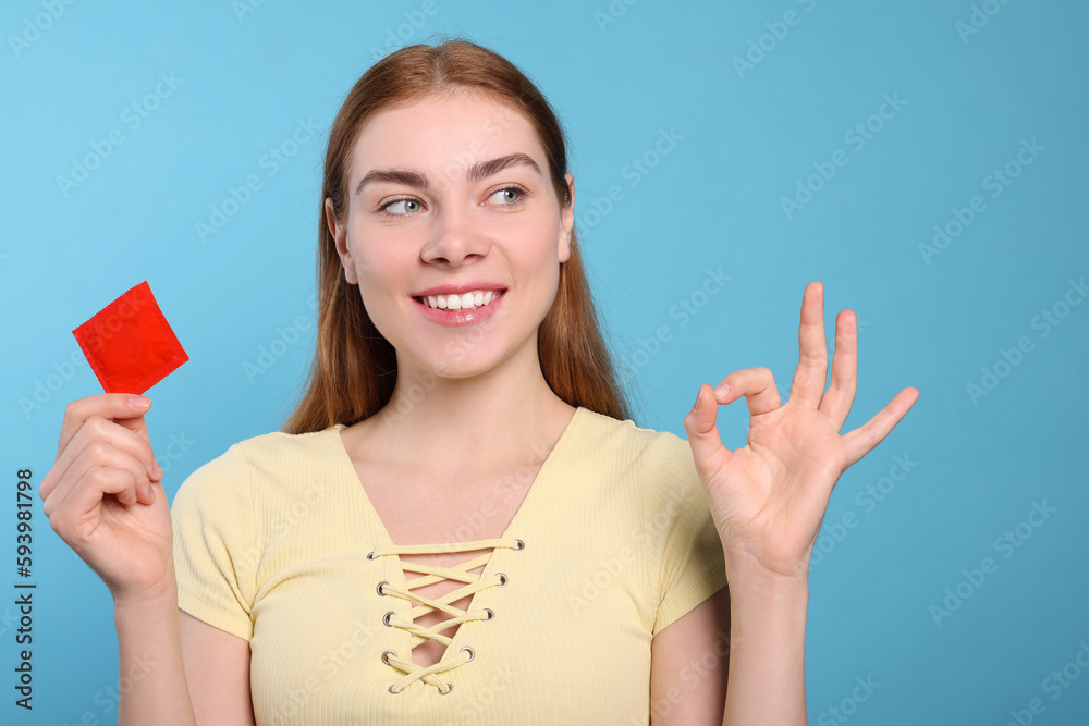 Woman with condom showing ok gesture on turquoise background. Safe sex Woman with condom showing ok gesture on turquoise background. Safe sex