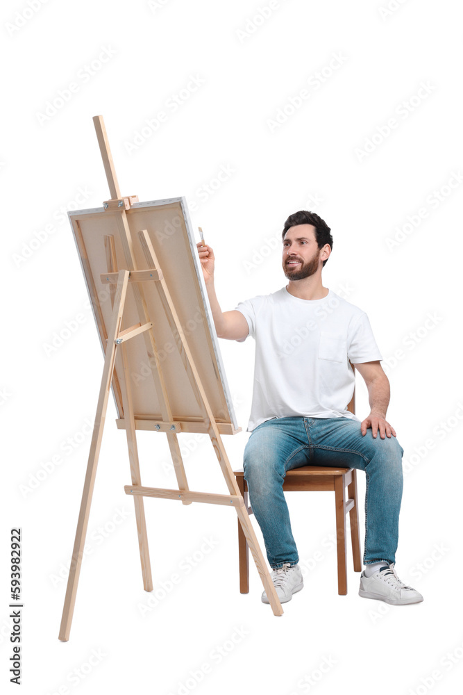 Man painting with brush against white background. Using easel to hold canvas