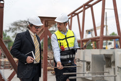 Businessman and male engineer discussing the quality of steel bar in concrete for making precast concrete wall at construction site.