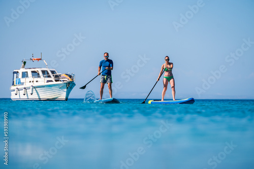 Couple riding SUP stand up paddle on vacation. © _jure