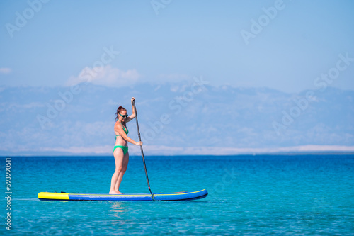 Woman riding SUP stand up paddle on vacation. © _jure