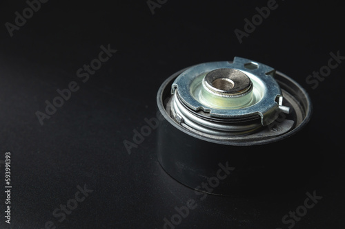 Close-up of a timing belt tensioner on a black background photo