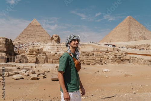 young man in a turban with great sphinx of Giza and pyramids in the background. El Cairo. Egypt