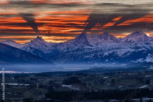 Scenic view of a rural town surrounded by beautiful snowy mountains during a mesmerizing sunset
