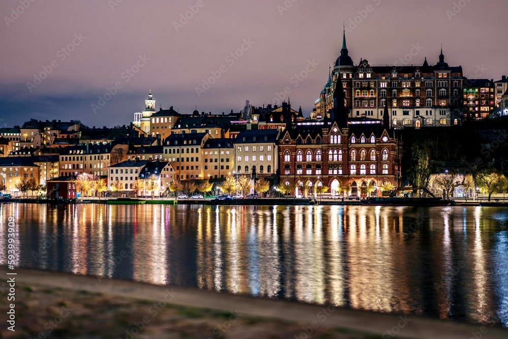 The Stockholm skyline, featuring illuminated buildings and their reflections in the dark water