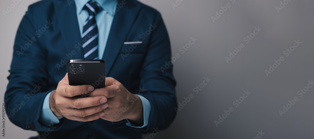 Close up view of young professional businessman using smartphone while standing in his office room. Close up view of young professional businessman using smartphone while standing in his office room.