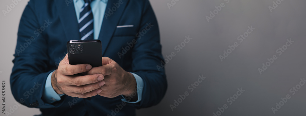 Close up view of young professional businessman using smartphone while standing in his office room. Close up view of young professional businessman using smartphone while standing in his office room.
