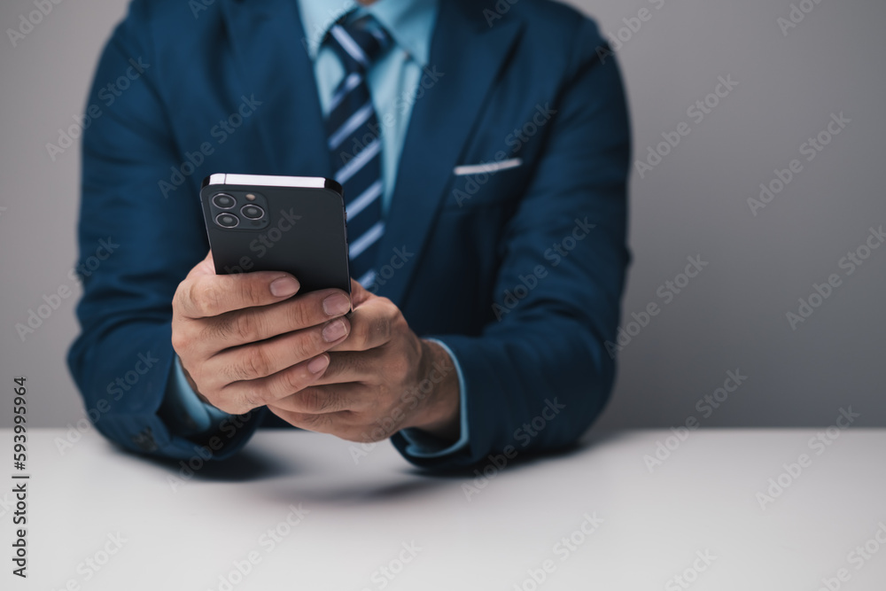 Close up view of young professional businessman using smartphone while sitting at his office desk.
