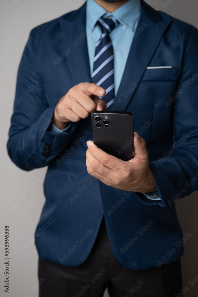 Close up view of young professional businessman using smartphone while standing in his office room. Close up view of young professional businessman using smartphone while standing in his office room.
