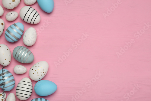 Flat lay composition with festively decorated Easter eggs on pink wooden table. Space for text