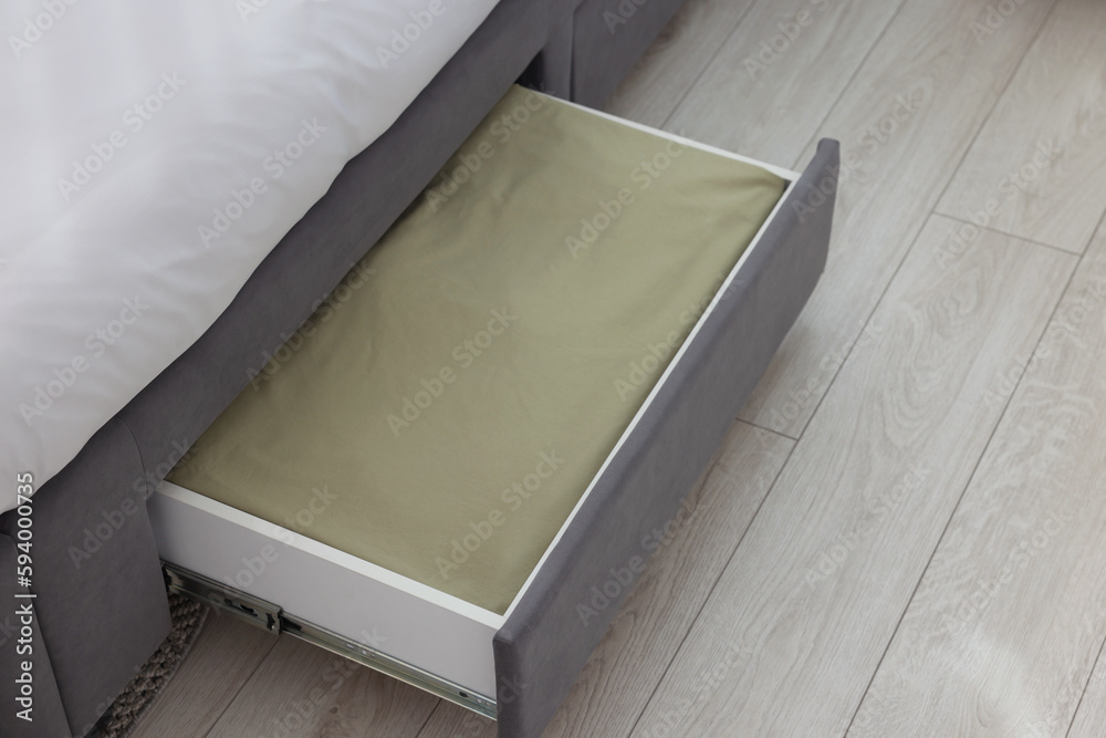 Storage drawer with bedding under comfortable bed in room Storage drawer with bedding under comfortable bed in room