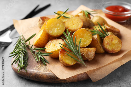 Photography Tasty baked potato and aromatic rosemary served on wooden board, closeup