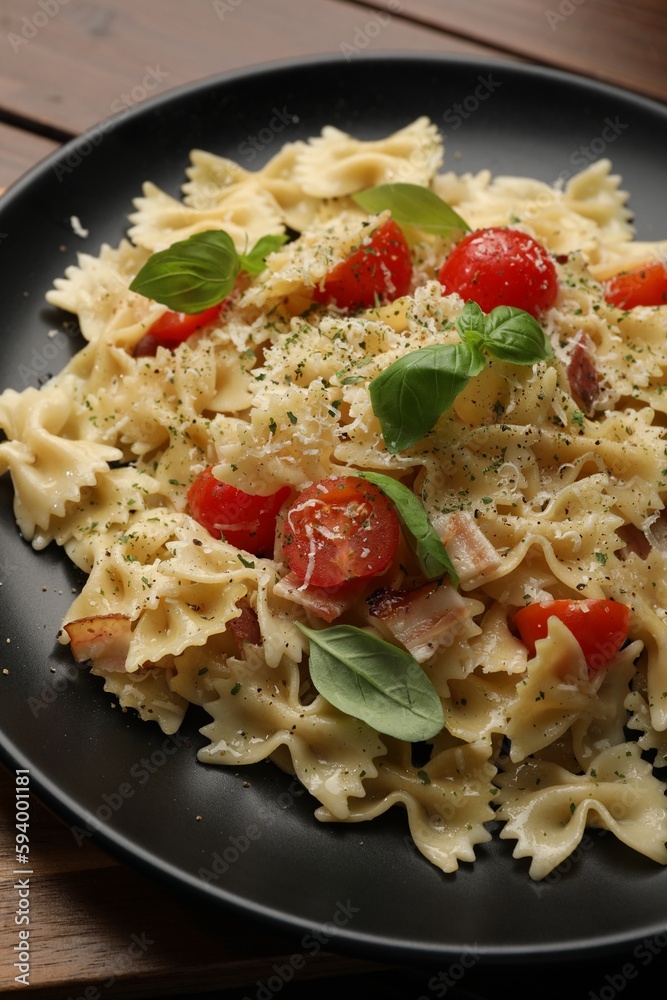 Plate of delicious pasta with tomatoes, basil and parmesan cheese on table, closeup Plate of delicious pasta with tomatoes, basil and parmesan cheese on table, closeup