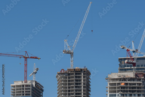 Canvas Print Construction cranes next to modern high rise tall condo and office building that are being built