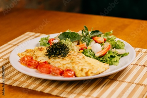 a plate topped with an omelette next to a salad