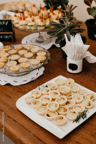 Assortment of delicious snacks and cookies arranged on white plates on a wood table