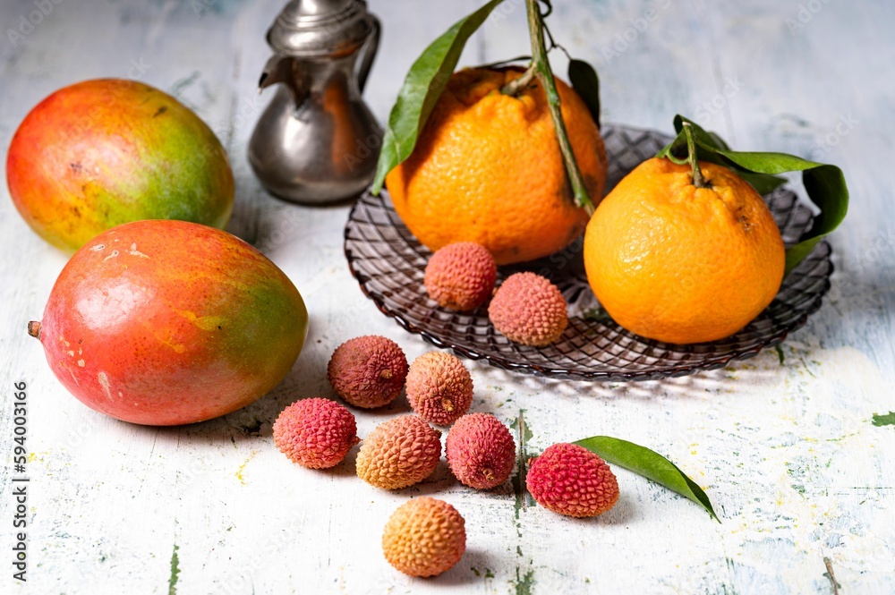 Litchis mangos and tangerines on a rustic wood background