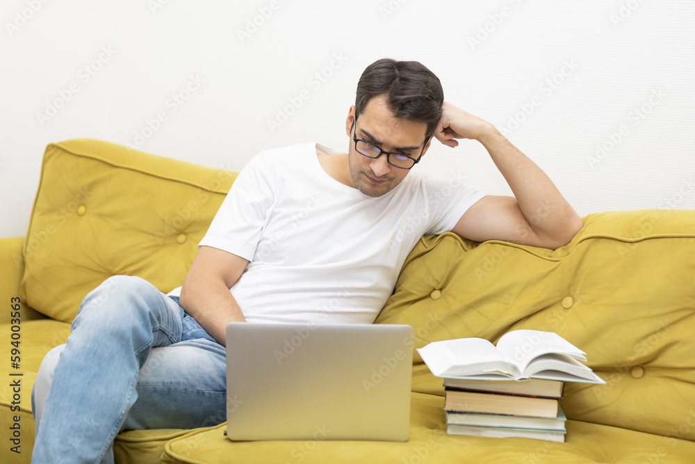 Upset and tired student sitting on the couch and studying online at home. Distance learning concept	