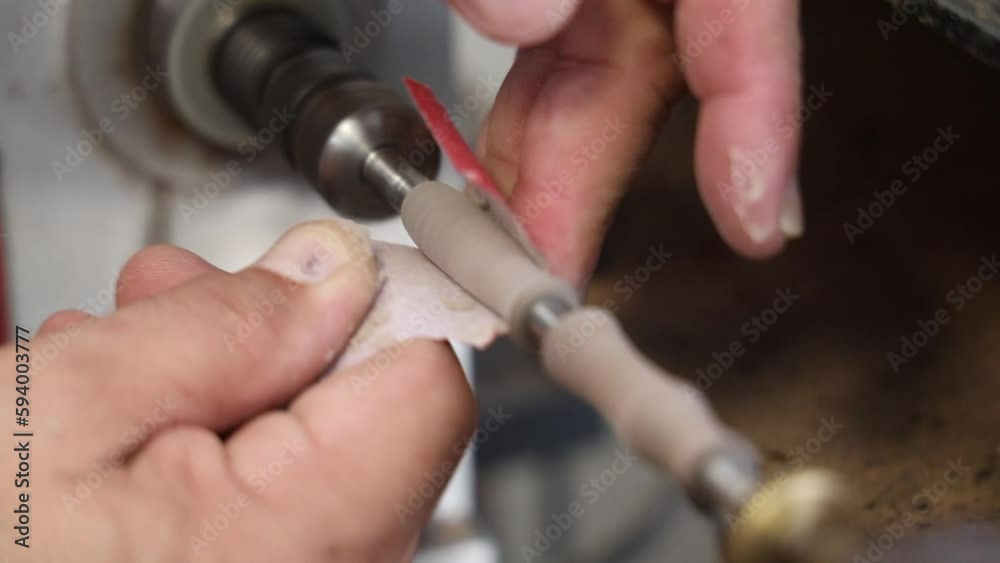 Artisan polishing craving wood by a paper on a lathe at a workshop Artisan polishing craving wood by a paper on a lathe at a workshop
