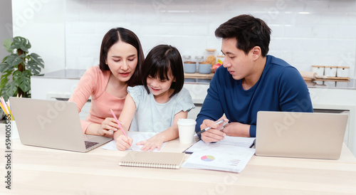 Beautiful woman And cute Asian girls drawing and writing on white paper The handsome man is working online. On the desk at home using a laptop via the internet It's a new normal life for the family.