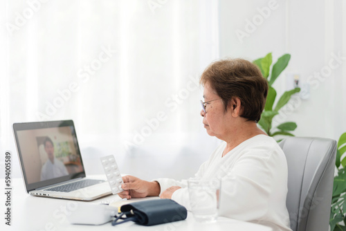 senior asian woman Meeting with a doctor via video call Using laptop from home, telemedicine and home healthcare.