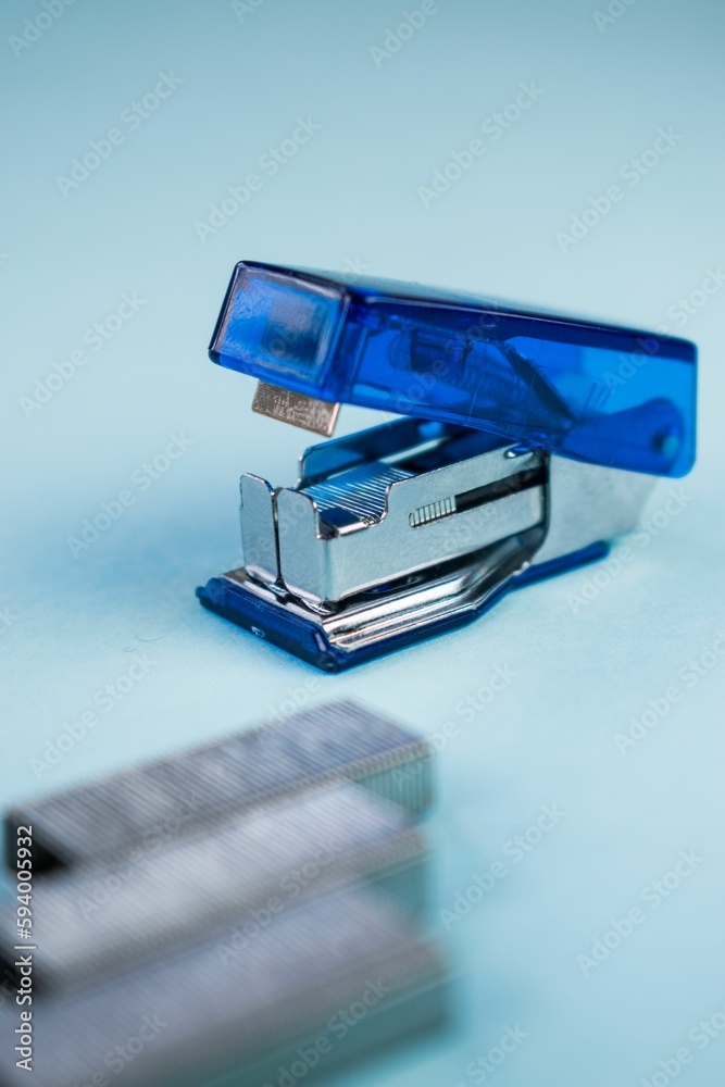 a stapler sitting next to a staple board on top of a blue surface a stapler sitting next to a staple board on top of a blue surface