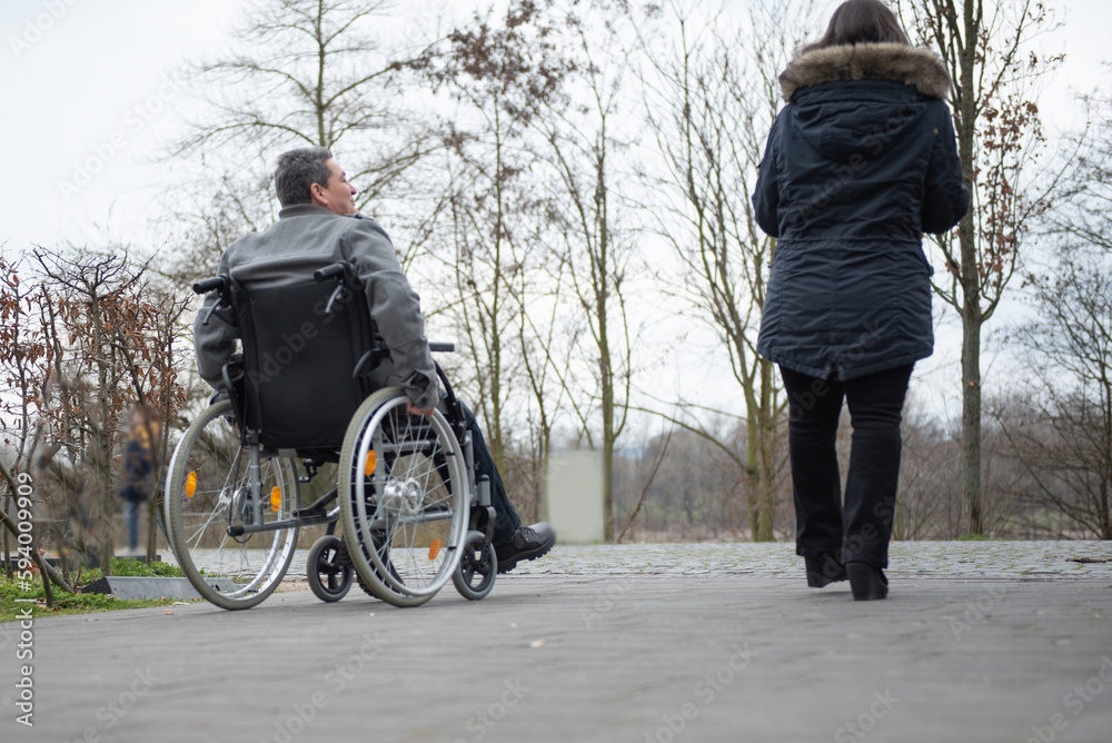 a physically disabled person on a wheelchair at a walk. a physically disabled person on a wheelchair at a walk.
