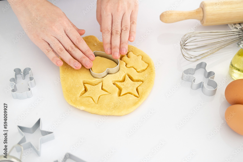 Woman preparing gingerbread cookies on white table at kitchen . Female hands cutting ginger dough with cutter to making cookies for winter holidays.copy space. Banner