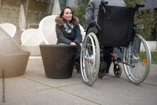 A woman talks to a disabled person in a wheelchair.