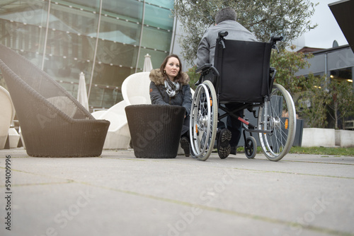A woman talks to a disabled person in a wheelchair.